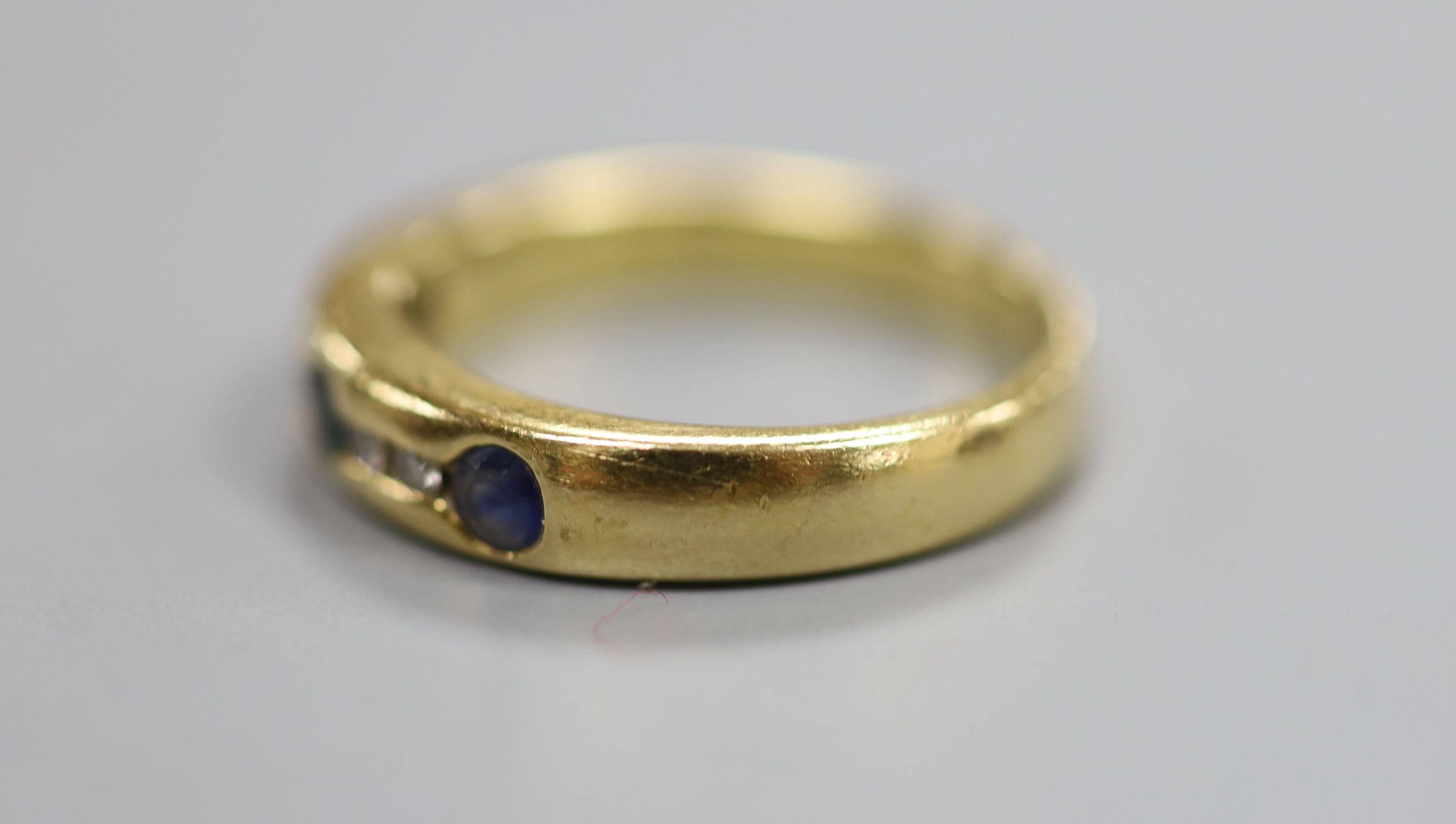 A modern 750 yellow metal, sapphire and diamond set half hoop ring, size N/O, gross 5.6 grams.